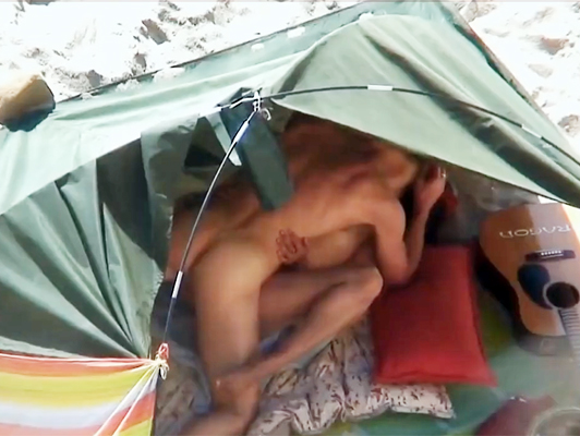 Imagen Voyeur con una cámara de video, filmando parejas follando en la playa